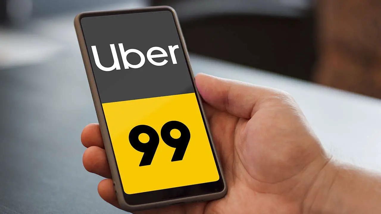 mão masculina segurando celular na tela aparece a logo do Uber e 99