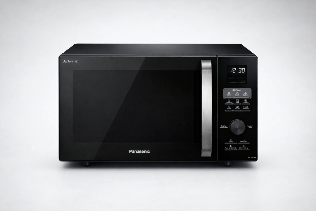 Fotografia em alta resolu&ccedil;&atilde;o de um forno micro-ondas Panasonic com fun&ccedil;&atilde;o AirFryer, acabamento preto fosco, porta de vidro refletivo, puxador met&aacute;lico e painel digital iluminado mostrando o hor&aacute;rio 12:30